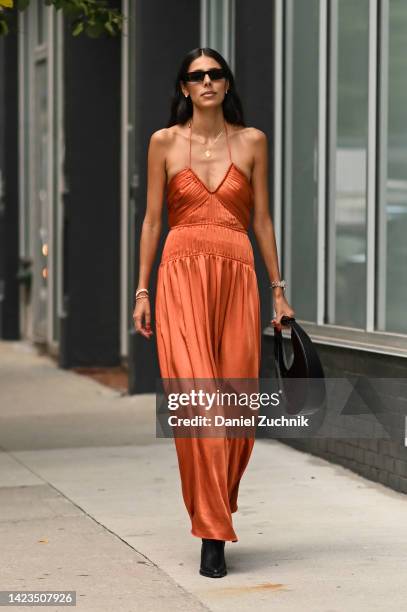 Babba Rivera is seen wearing black sunglasses, an orange Jonathan Simkhai dress, black bag and black boots outside the Jonathan Simkhai show during...