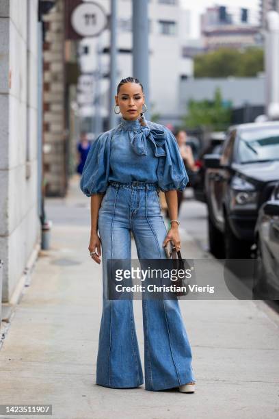 Guest wearing flared denim jeans, top, Gucci bag outside Gabriela Hearst on September 13, 2022 in New York City.