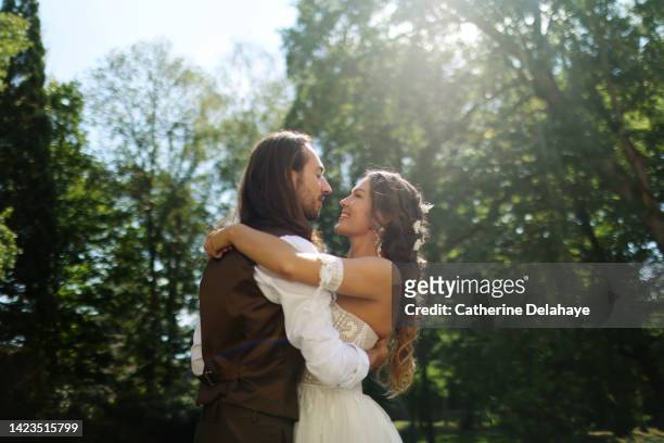 a newlyweds couple posing together in a garden - europe bride stock-fotos und bilder