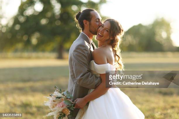 a newlyweds couple posing together in the countryside - koninklijke bruiloft stockfoto's en -beelden