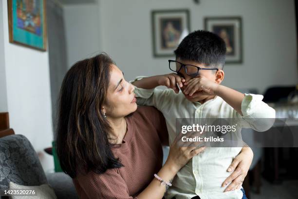 madre che conforta il suo piccolo figlio a casa - boy indian foto e immagini stock