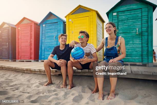 three teenagers sitting at alicante beach in front of beach cubicles - young boys changing in locker room 個照片及圖片檔