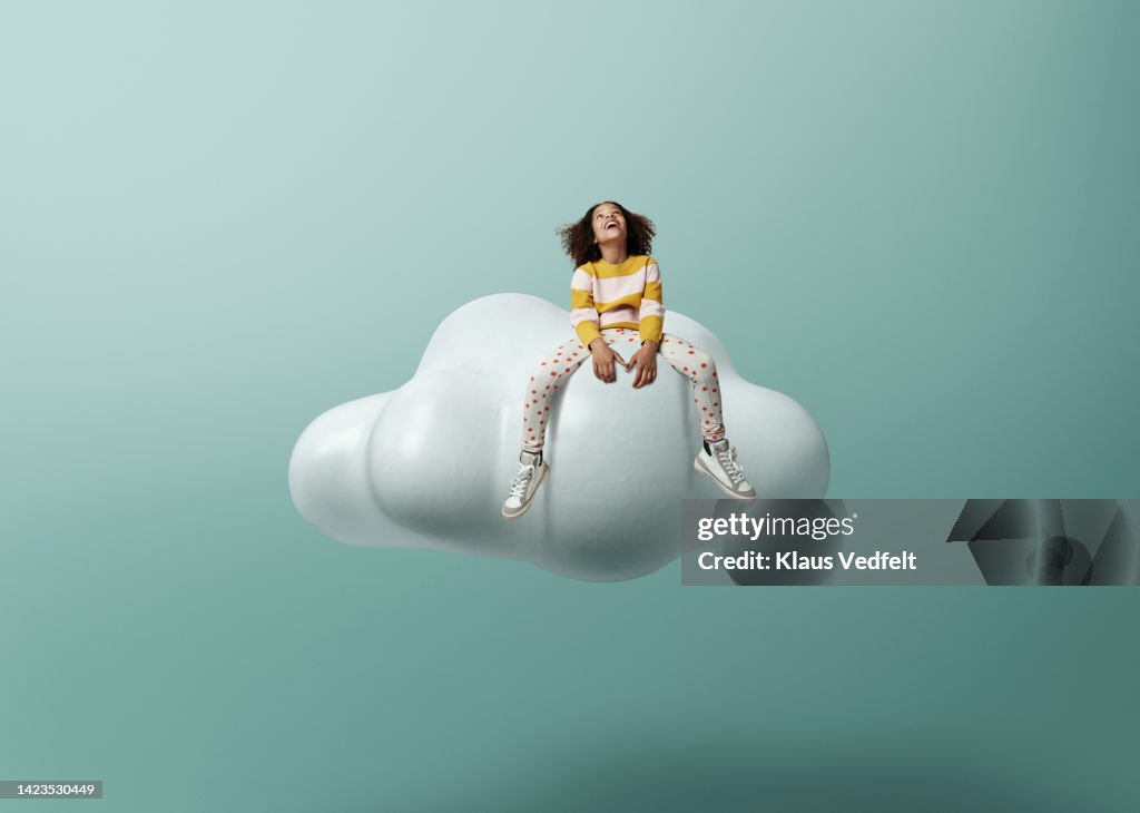 Girl laughing while sitting on cloud
