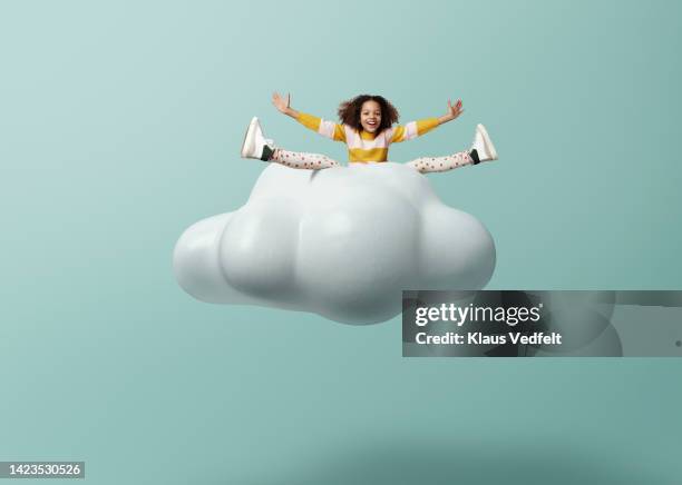 girl with arms outstretched and legs apart on cloud - girl shoes stock-fotos und bilder