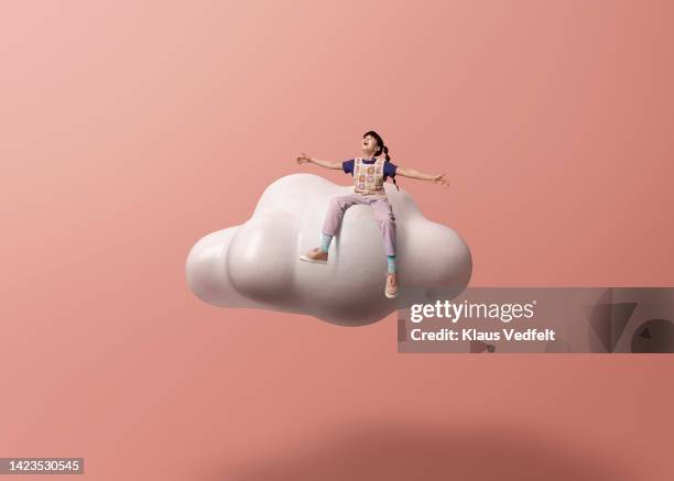 girl with arms outstretched sitting on cloud - sitting on a cloud foto e immagini stock