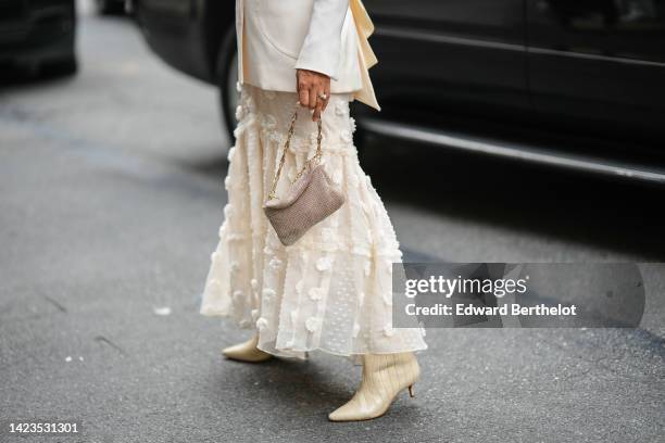 Guest wears a white latte long blazer jacket, a white latte ruffled with embroidered lace flower pattern long skirt, a gold rhinestones handbag,...