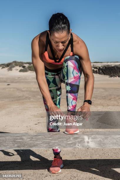 female runner tying her shoe laces - sportlerin stock-fotos und bilder