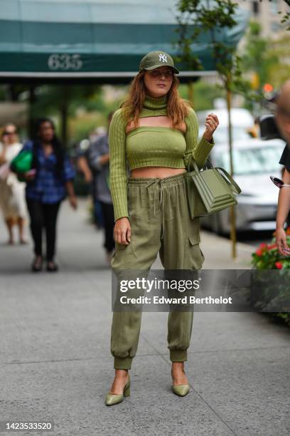 Guest wears a khaki cap from New Era, a green ribbed wool / turtleneck / long sleeves / cut-out chest / cropped pullover, a khaki matte leather...