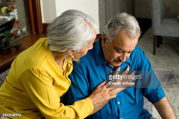 wife comforting her husband suffering with severe chest pain - heart attack stock pictures, royalty-free photos & images