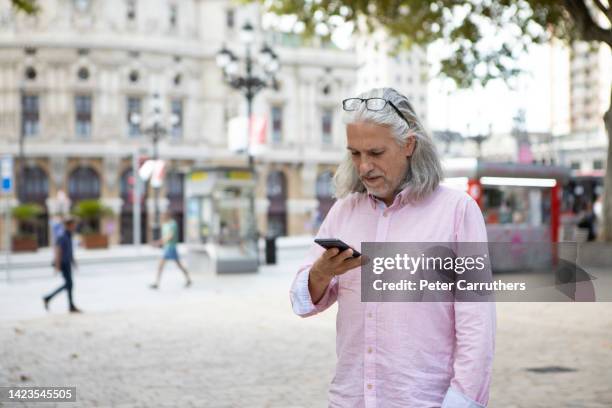 mid adult male using a mobile phone in a spanish city centre - bilbao spain stock pictures, royalty-free photos & images