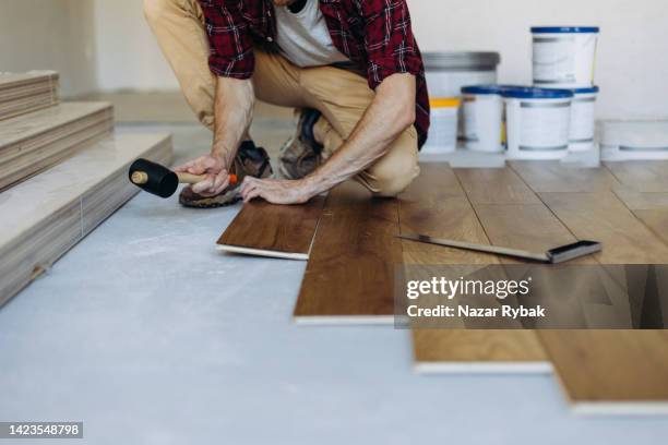 installando il pavimento in parquet, un uomo mani che fissano una piastrella con un martello - legno duro foto e immagini stock