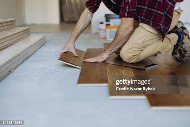 the man is installing the wooden plank of the parquet floor - flooring contractor stock pictures, royalty-free photos & images