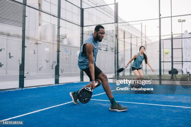 friends playing paddle tennis on outdoor court - racket stock pictures, royalty-free photos & images