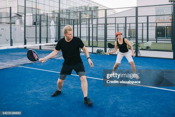 instructor teaching paddle tennis to senior woman - pudel stock pictures, royalty-free photos & images
