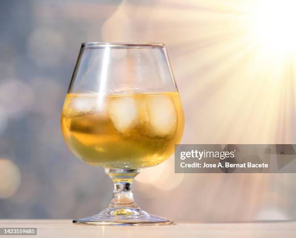 liquor glass with ice lit by sunlight. - glass half full party stock pictures, royalty-free photos & images