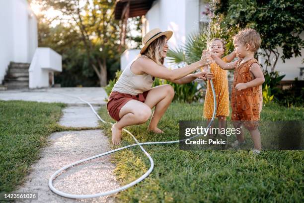 lustige zeiten mit mutter in einem hinterhof - kind wasser stock-fotos und bilder