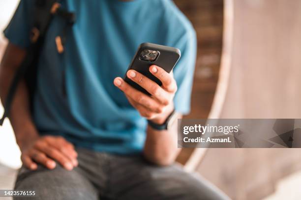 cool young african american male using a smart phone while commuting in the city - surfing the net stock pictures, royalty-free photos & images