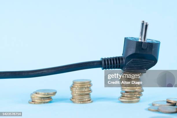 period of inflation: electricity has become expensive. power cable on a pile of coins. - prise électrique photos et images de collection