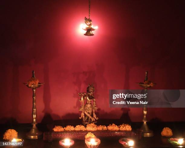 brass lord krishna idol decorated with  lit clay diyas' and marigold flowers during diwali/deepavali festival/india - krishna bildbanksfoton och bilder