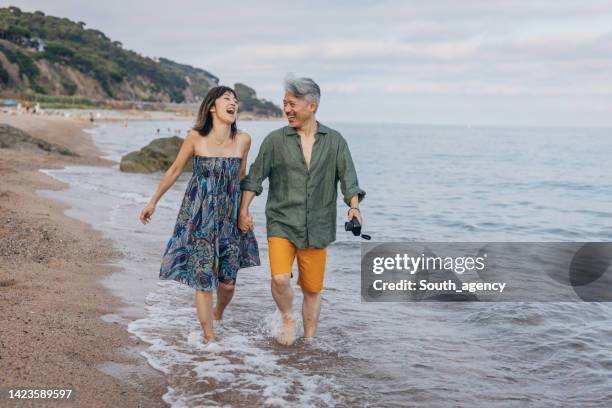 attraktive brautpaar zu fuß auf schönen sonnenstrand - positive healthy middle age woman stock-fotos und bilder