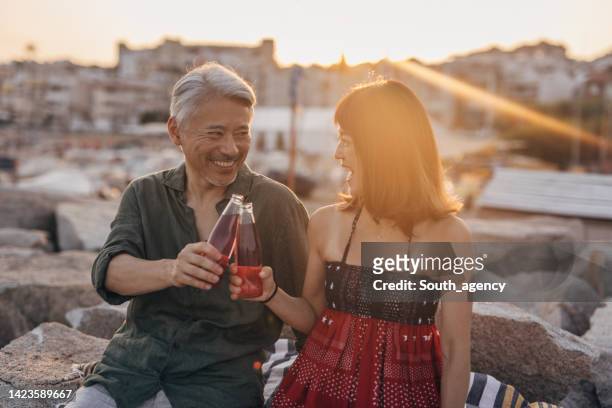happy couple drinking soda on a date by the beach - asian female friends drinking soda outdoor stockfoto's en -beelden