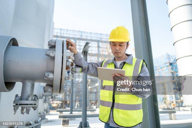 a male engineer was checking equipment in a chemical plant with a tablet computer - gas engineer stockfoto's en -beelden