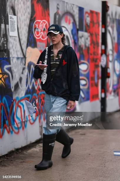 Guest seen wearing a navy blue cap, glasses, green polo shirt, dark blue zip hoodie jacket, blue denim jeans, white leather Balenciaga Cagole bag and...