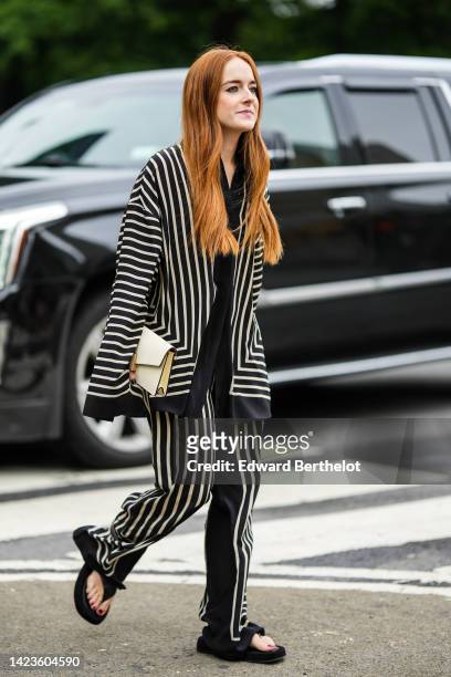 Guest wears a black with white latte striped print pattern oversized silk shirt, matching black with white latte striped print pattern large silk...