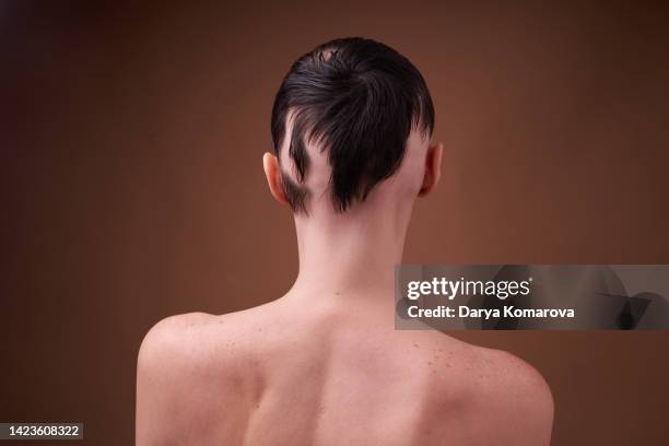 a young woman with alopecia. hair loss problem, young woman from behind in profile with baldness on a beige background. brunette shirtless woman. the concept of human support, female power, social inequality - alopecia fotografías e imágenes de stock