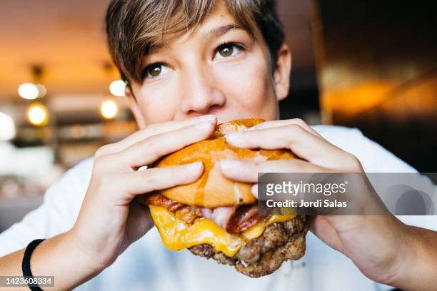 teenager eating a burger - kid eating burger bildbanksfoton och bilder