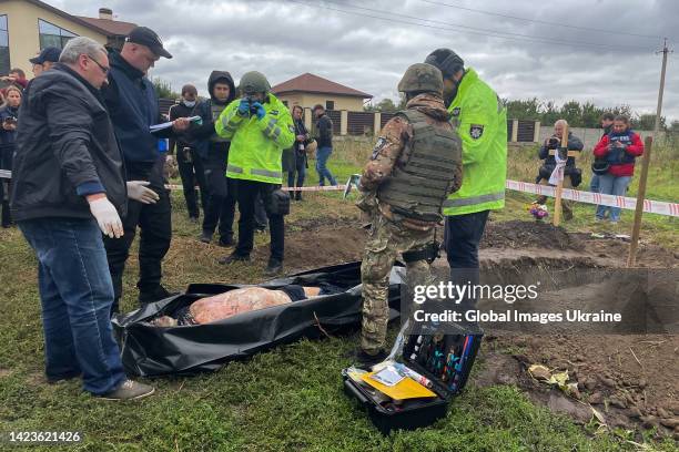 Ukrainian policemen and criminalist stand near exhumed body of civilian who was shot dead by Russian soldiers ahead of the liberation of the city on...