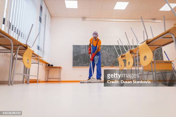 operatore sanitario che pulisce il pavimento in classe - bidello foto e immagini stock
