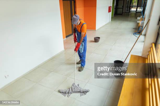 senior adult janitor mopping floor at school - school caretaker stock pictures, royalty-free photos & images