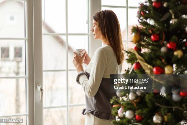 looking at the winter outside the window while staying warm with a cup of tea - staying indoors stock pictures, royalty-free photos & images