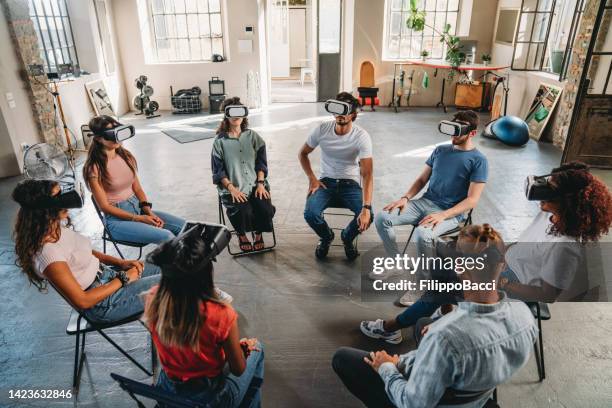 group of people sitting in circle wearing virtual reality vr glasses during a meditation group therapy session - group counselling stock pictures, royalty-free photos & images