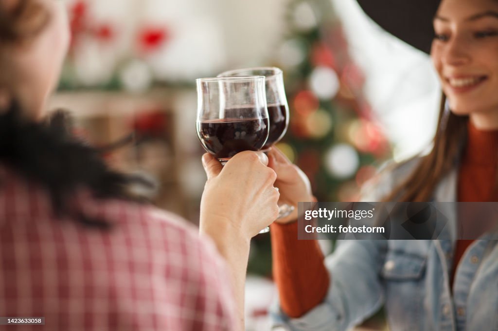 Mother and daughter wearing Halloween costumes and cheering with glasses of red wine