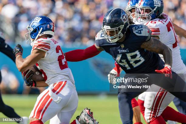 Bud Dupree of the Tennessee Titans reaches out to tackle Saquon Barkley of the New York Giants at Nissan Stadium on September 11, 2022 in Nashville,...