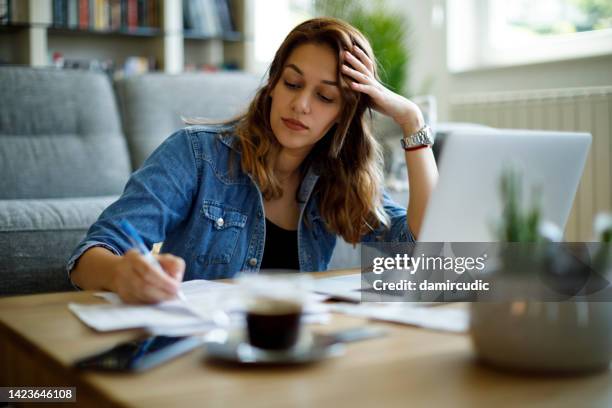 young worried woman going over finances at home - student debt stock pictures, royalty-free photos & images