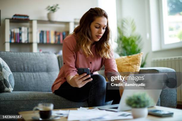 junge frau, die zu hause finanzen berechnet - akin stock-fotos und bilder