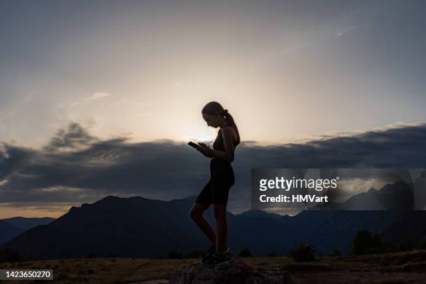 girl using a phone while running in nature, alpine meadow at the sunset - young athletes stock pictures, royalty-free photos & images