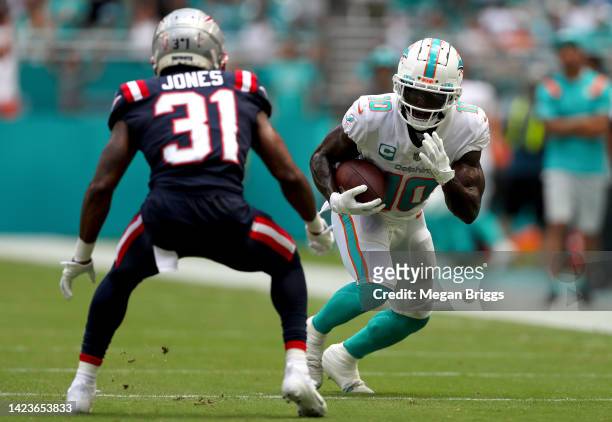 Tyreek Hill of the Miami Dolphins carries the ball against Jonathan Jones of the New England Patriots during the first half at Hard Rock Stadium on...
