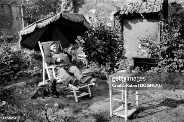 Happy man in his garden sitting on deckchair, Vitry, France in 1965.