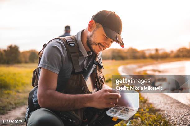 caucasian guy taking a fishing lure out - young men fishing stock pictures, royalty-free photos & images