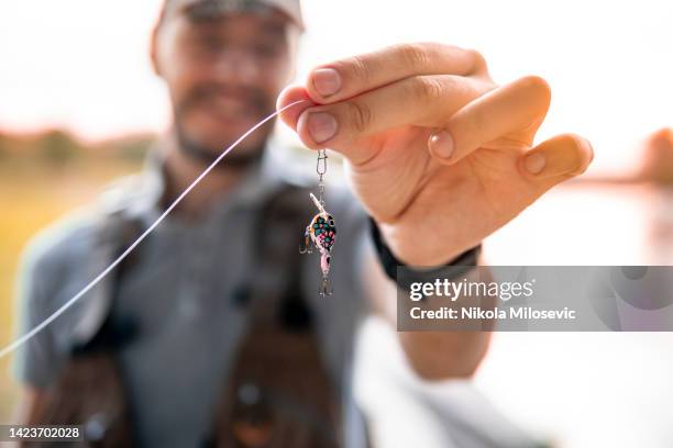 cara caucasiano mostrando uma isca de pesca - linha de pesca - fotografias e filmes do acervo