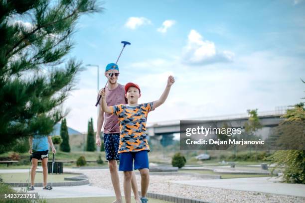 jungen, die minigolf spielen - mini golf stock-fotos und bilder