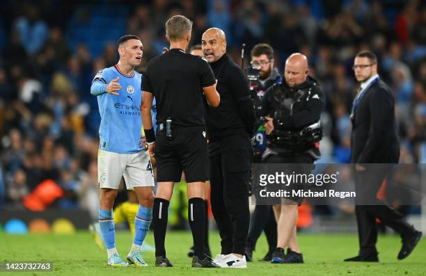 Pep Guardiola, Manager of Manchester City interacts with match referee Daniele Orsato after receiving a yellow card during the UEFA Champions League...
