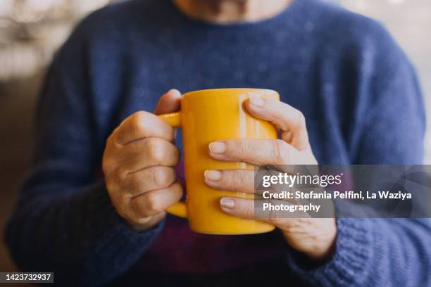 close up on senior woman's hands holding a coffee mug - drinking tea in a cup stock pictures, royalty-free photos & images