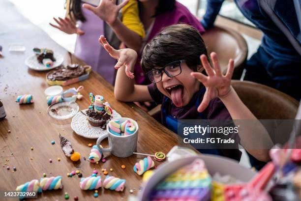 retrato de un niño jugando con dulces en un día infantil en casa - poner caras fotografías e imágenes de stock
