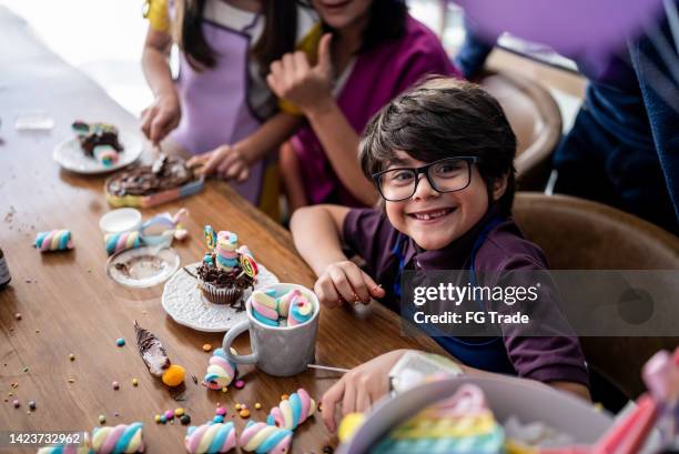 ritratto di un ragazzo che gioca con i dolci in una giornata dei bambini a casa - giorno dei bambini foto e immagini stock