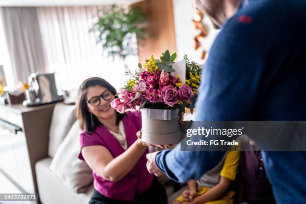 ehefrau erhält eine geschenkbox mit einem blumenstrauß von ihrem mann zu hause - woman giving flowers stock-fotos und bilder